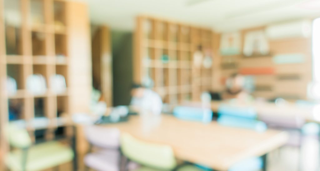 School classroom in blur background without young student; Blurry view of elementary class room no kid or teacher with chairs and tables in campus. Vintage effect style pictures.
